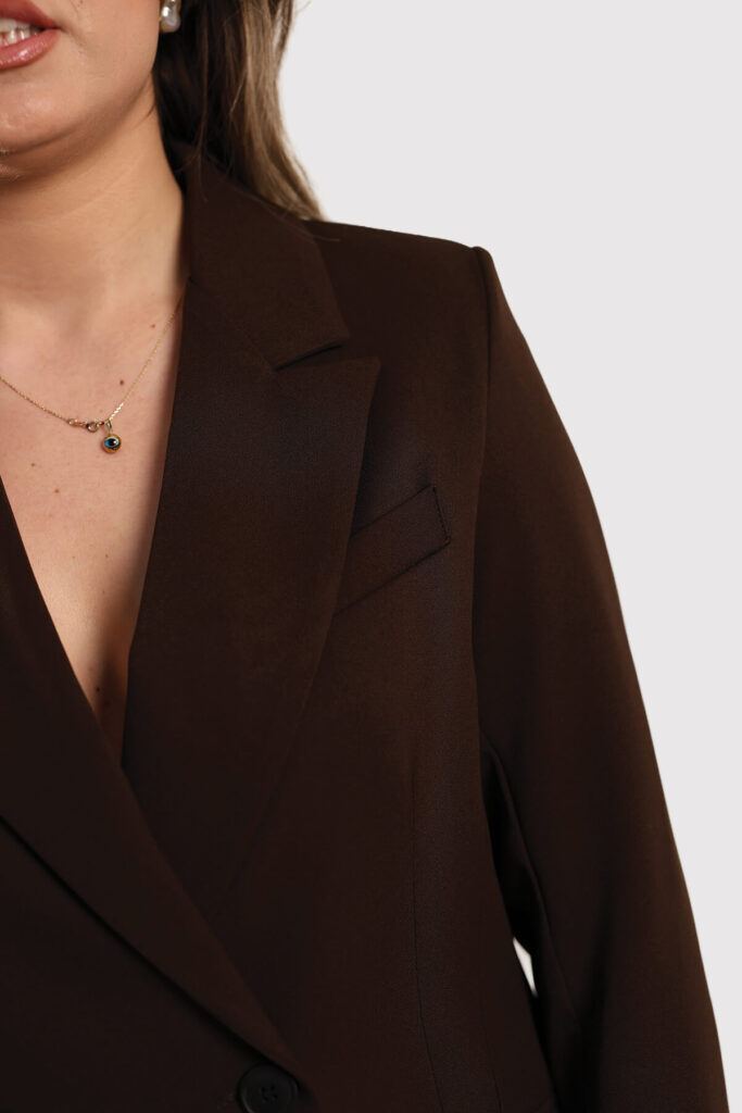 A model dressed in a beige sweater and matching pants stands confidently, showcasing a casual yet stylish outfit