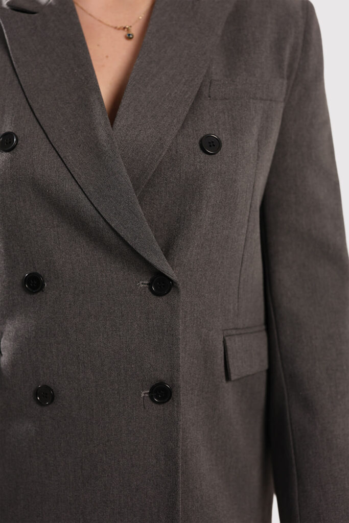 A model dressed in a beige sweater and matching pants stands confidently, showcasing a casual yet stylish outfit