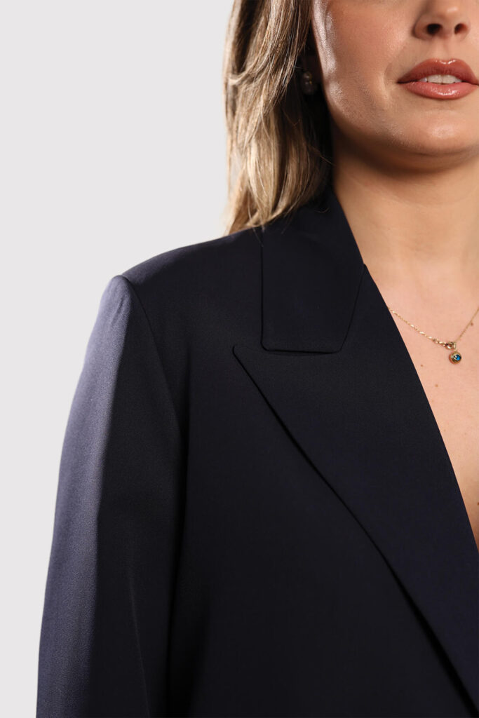 A model dressed in a beige sweater and matching pants stands confidently, showcasing a casual yet stylish outfit